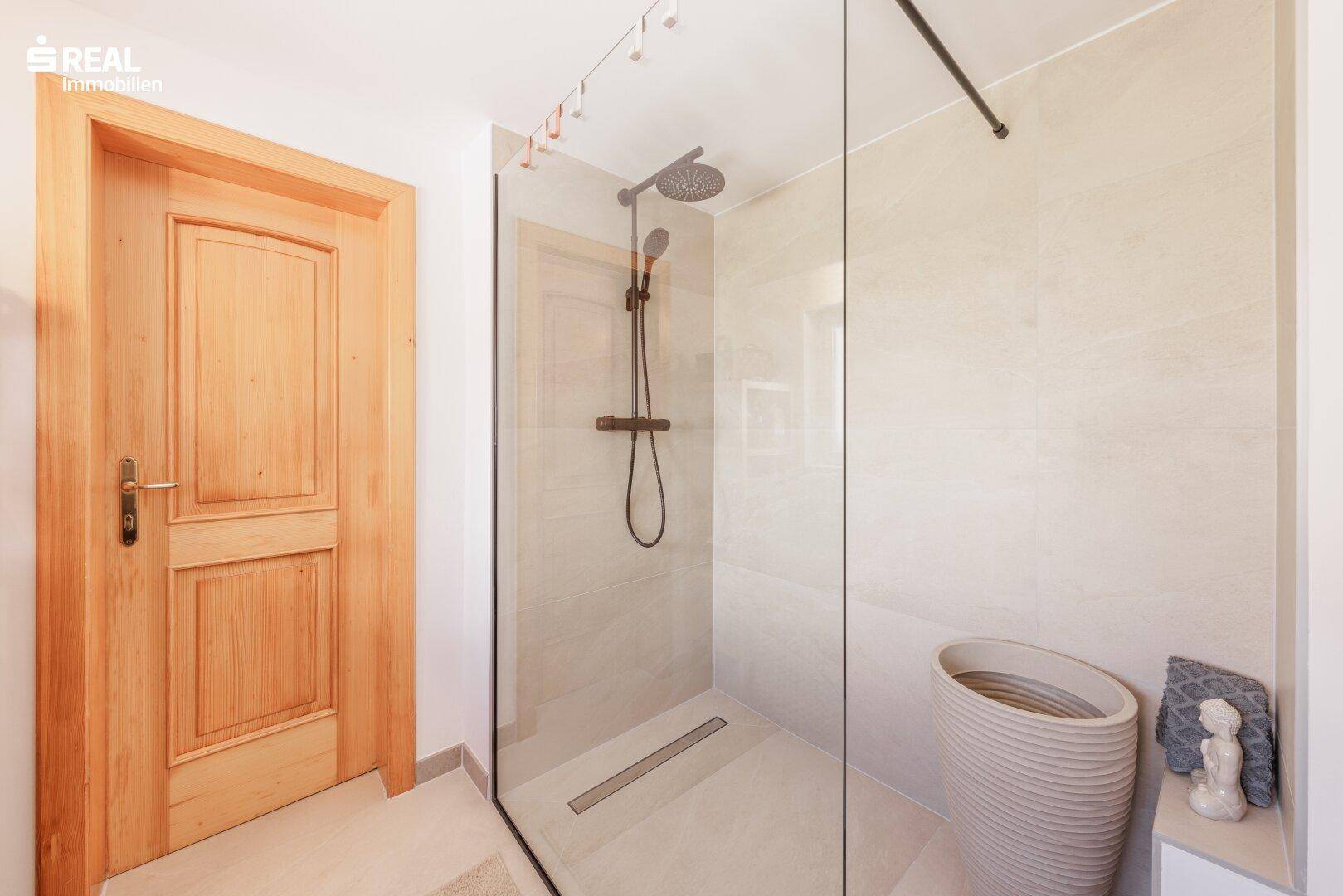 Modernes Badezimmer mit ebenerdiger Dusche und hellen Fliesen, bietet hohen Komfort und Stil.