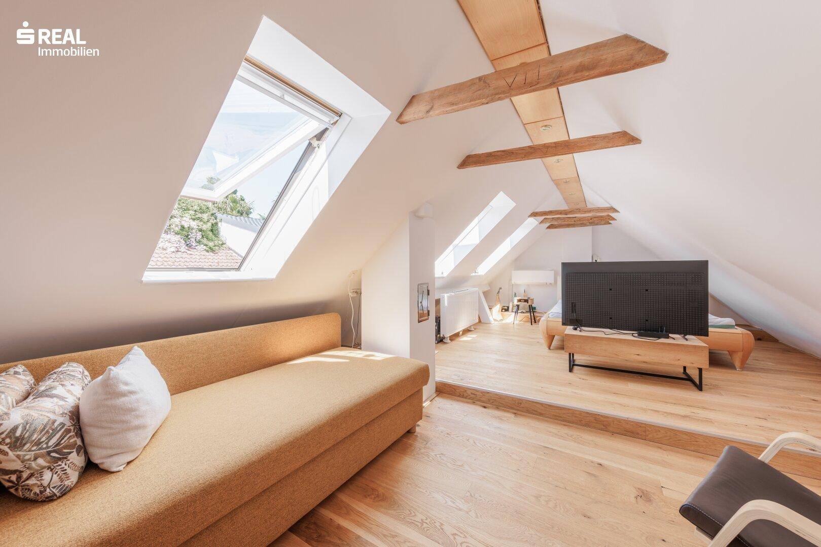 Geräumiges Dachzimmer mit Holzboden, mehreren Dachfenstern und TV-Bereich, bietet vielseitige Nutzungsmöglichkeiten.