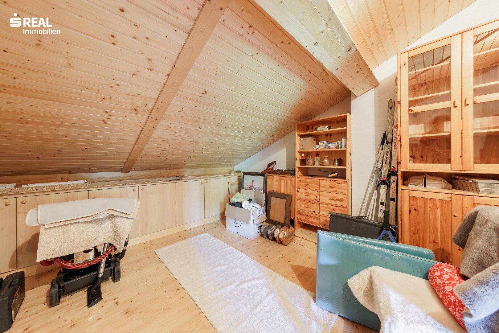 Dachbodenraum mit Holzdecke, Holzboden und praktischen Einbauschränken, ideal als zusätzlicher Stauraum.