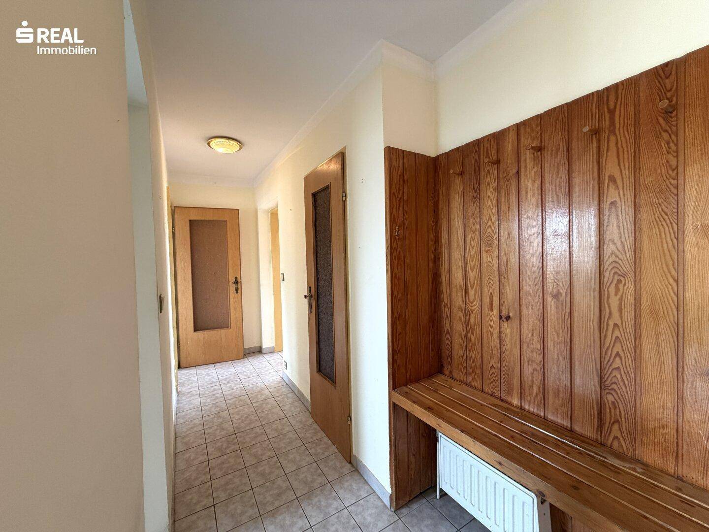 Heller Flur mit Fliesenboden, Holzvertäfelung und einer praktischen Sitzbank.