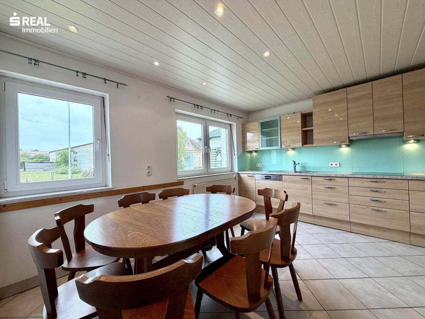 Geräumige Wohnküche mit Holztisch, modernen Einbauschränken und Fliesenboden.