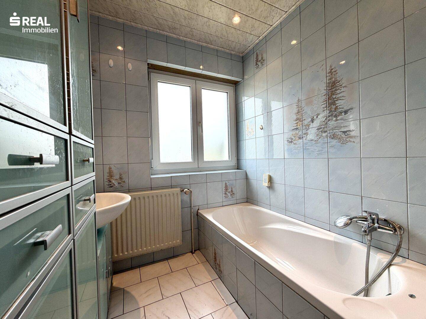 Badezimmer mit Badewanne, Waschbecken und hellblauen Fliesen im traditionellen Stil.