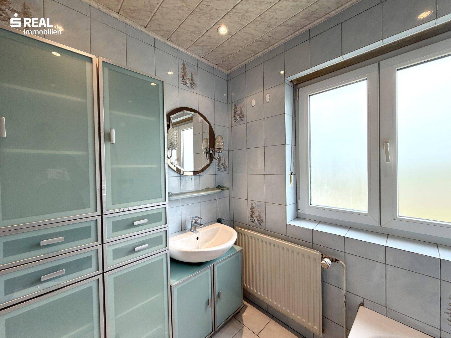 Badezimmer mit Waschbecken, Spiegelschrank und hellblauen Fliesen im traditionellen Stil.