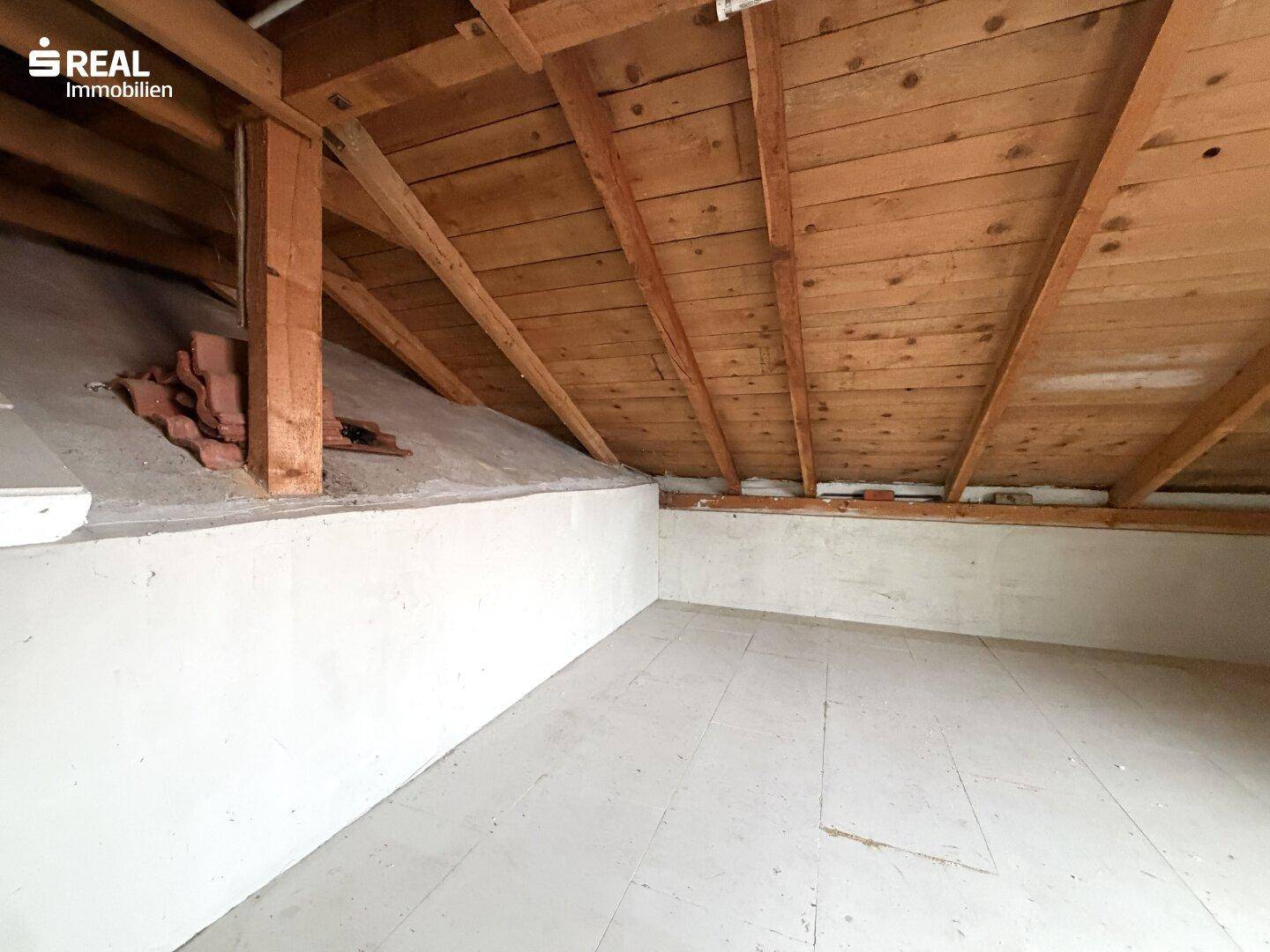 Unausgebauter Dachboden mit sichtbarer Holzkonstruktion und Stauraum.