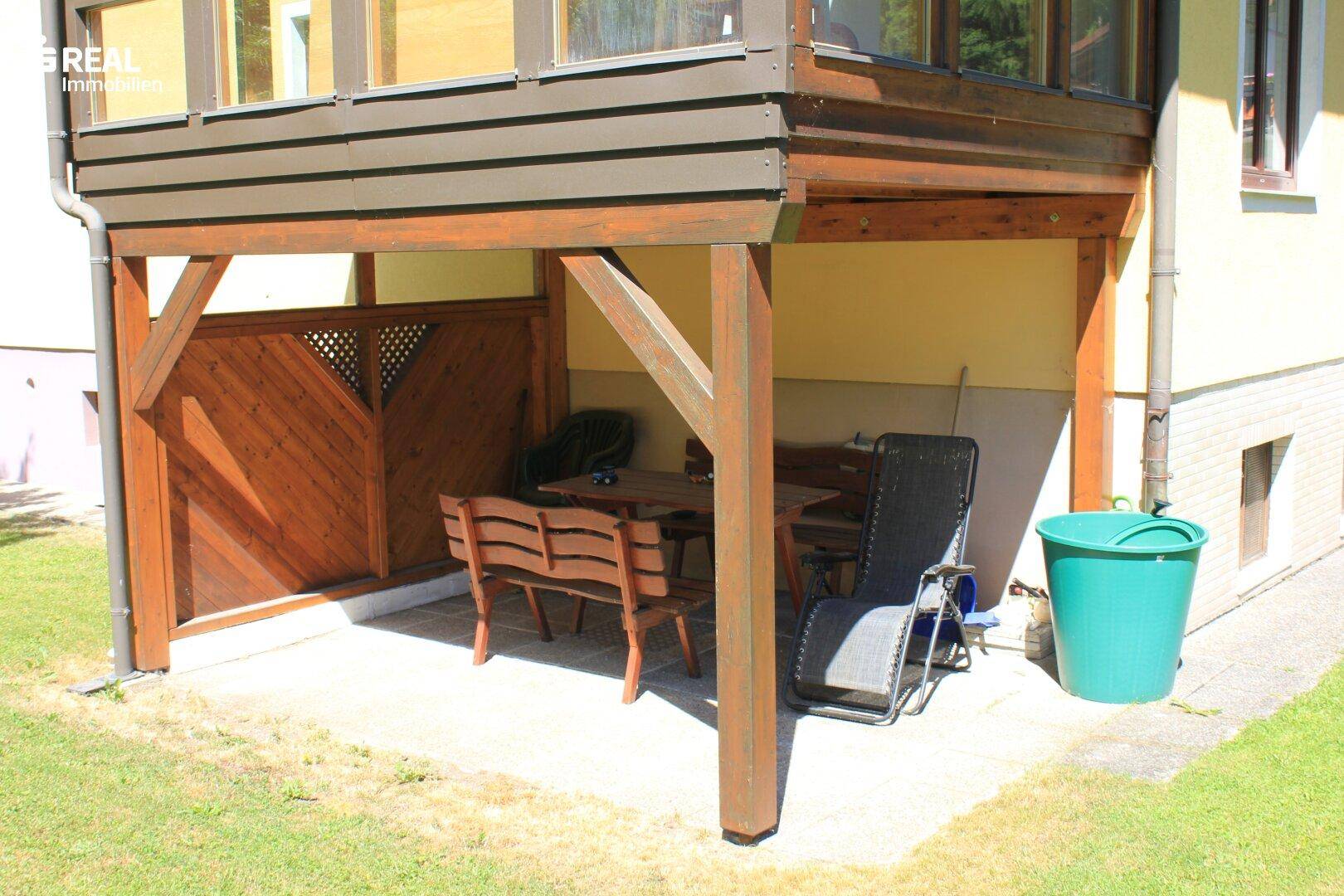 Überdachter Sitzbereich im Freien mit Holzbänken und Tisch, ideal für entspannte Stunden.