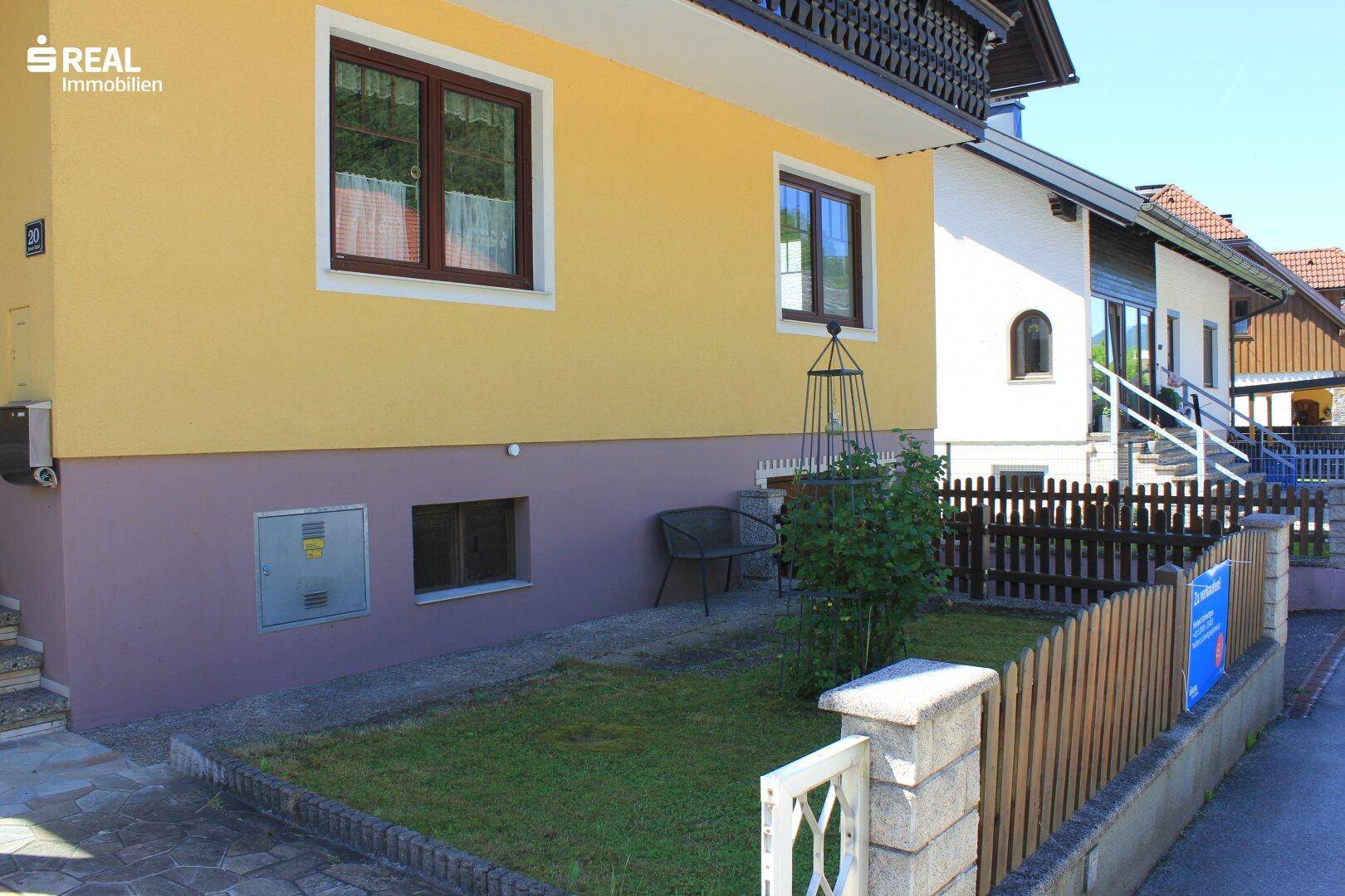 Kleiner Vorgartenbereich mit Rasenfläche und Zaun, angrenzend an die Hausfassade.