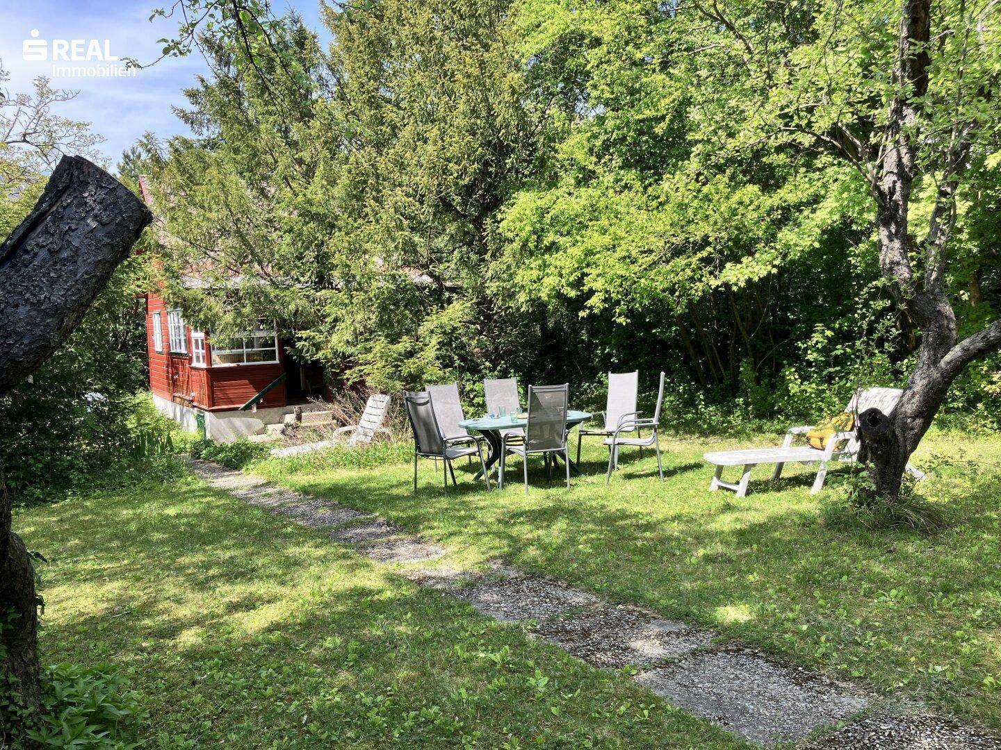 Geräumiger Garten mit Esstisch, Stühlen und Liegestuhl, ideal für entspannte Stunden im Freien.