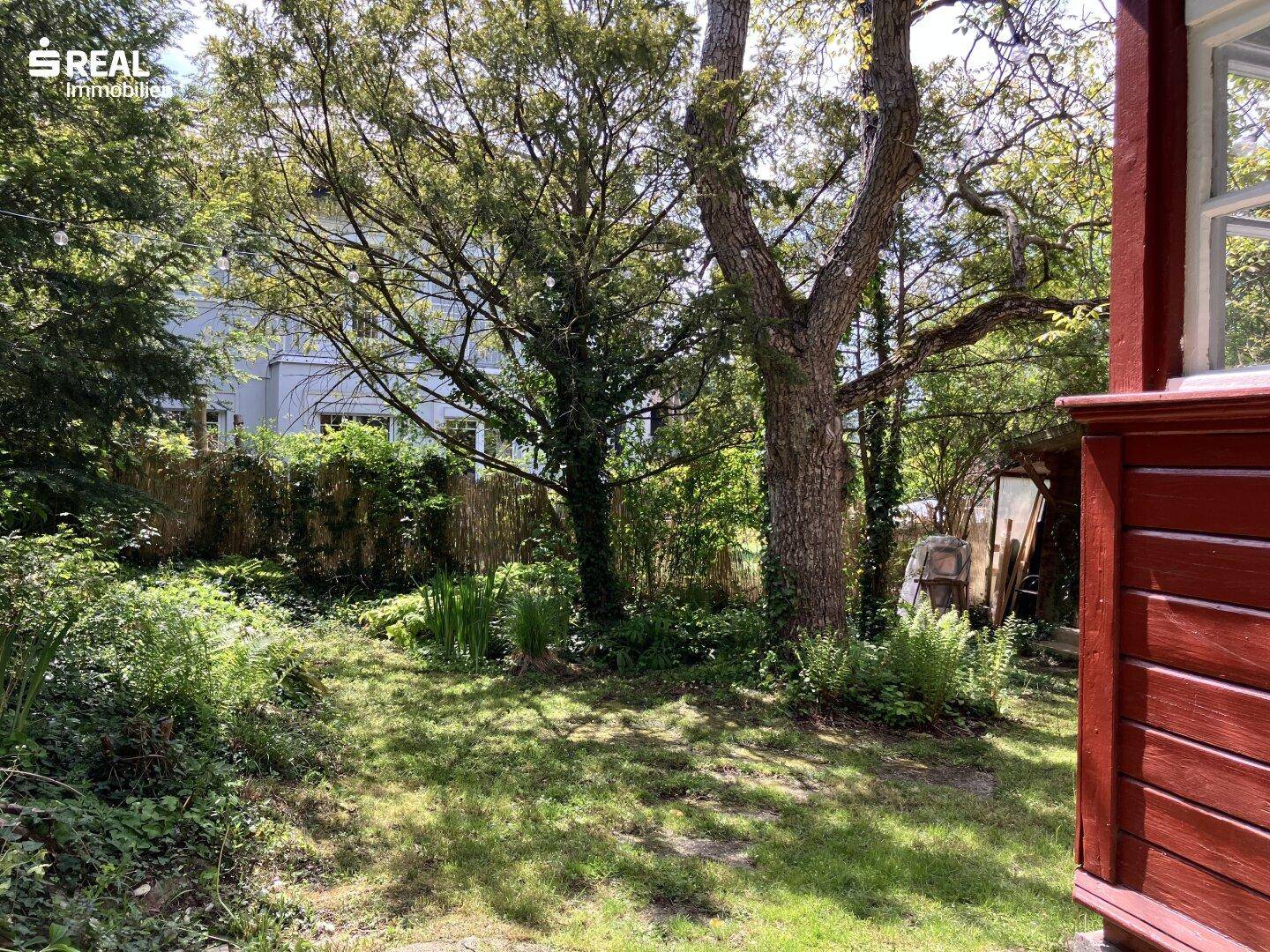 Großer, grüner Gartenbereich mit alten Bäumen und dichter Bepflanzung, umgeben von Natur.