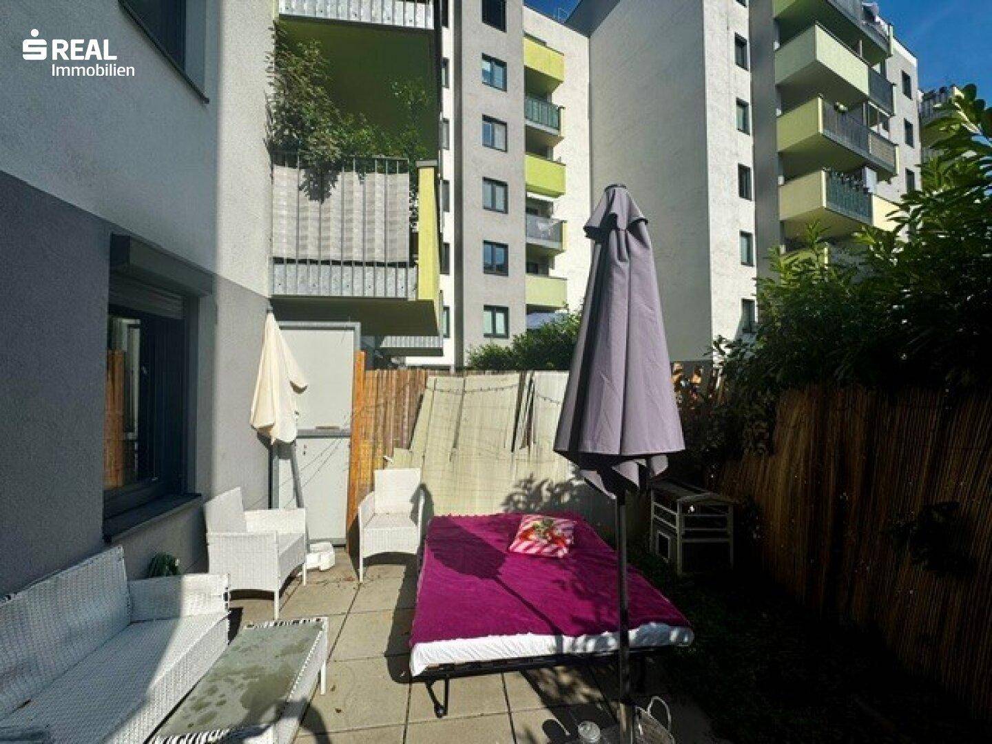 Gemütliche Terrasse mit Lounge-Möbeln und Liegefläche, umgeben von Grün und Sichtschutz.