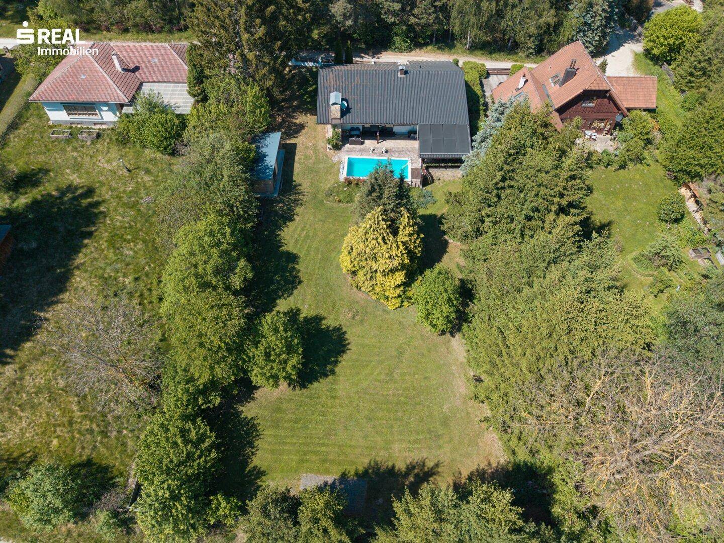 Weitläufige Luftaufnahme des Anwesens mit großem Rasen, Haus und Swimmingpool.
