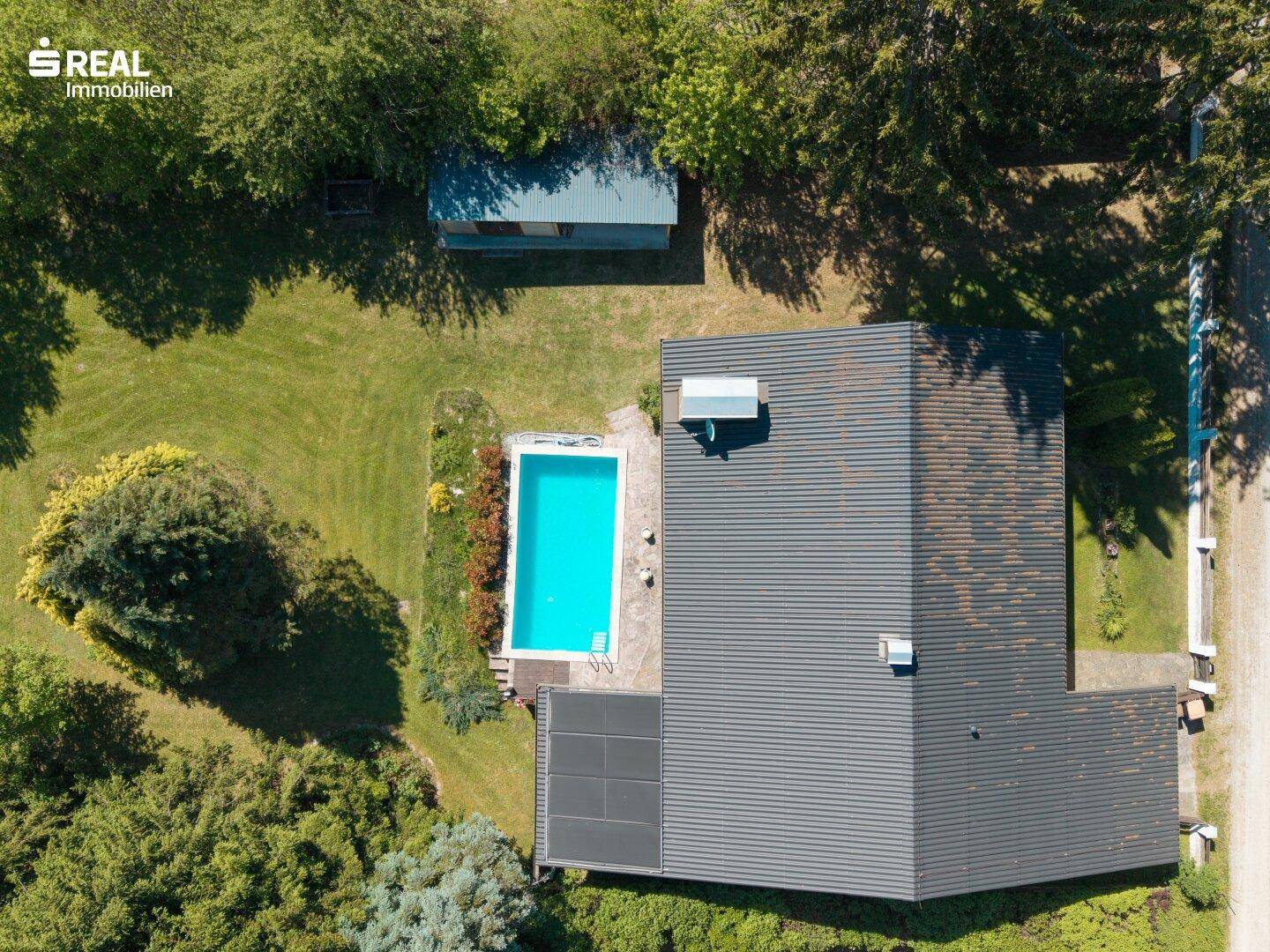 Vogelperspektive des Hauses mit Swimmingpool und angrenzender Terrasse, umgeben von Bäumen.
