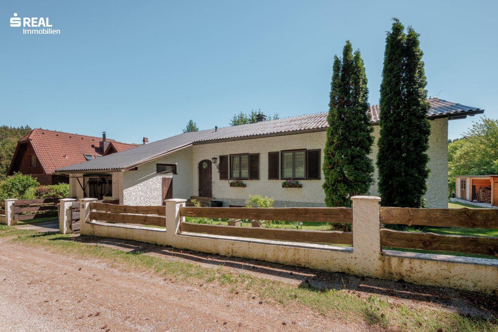 Hausansicht von der Straße mit traditionellem Holzzaun und gepflegtem Vorgarten.