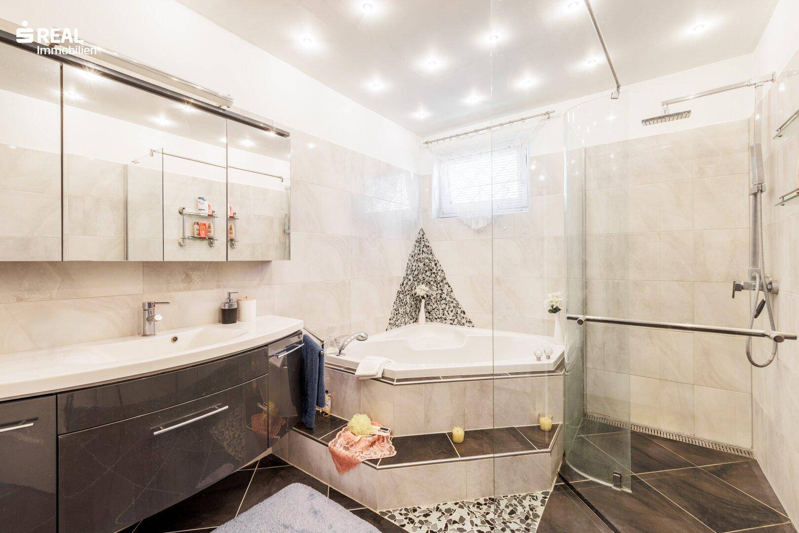 Modernes Badezimmer mit Eckbadewanne, begehbarer Dusche und Doppelwaschbecken.