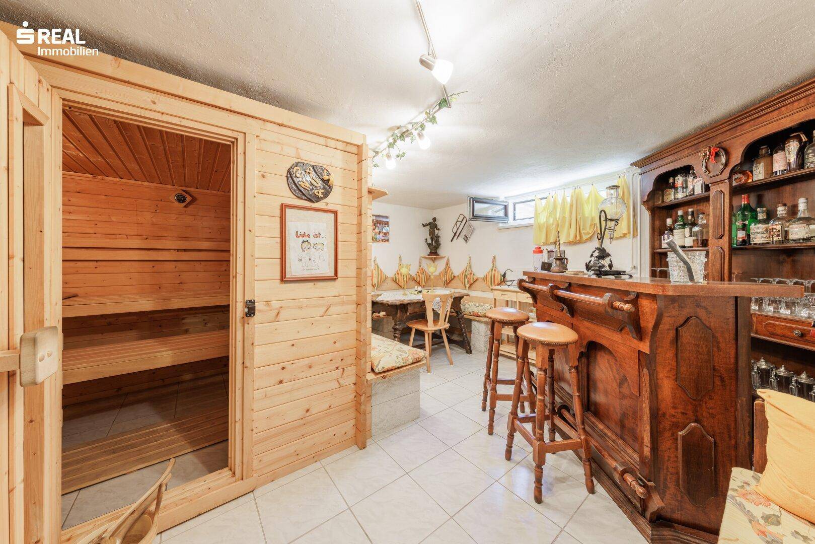 Gemütlicher Wellnessbereich im Keller mit Sauna, Holzbar und rustikaler Sitzecke.
