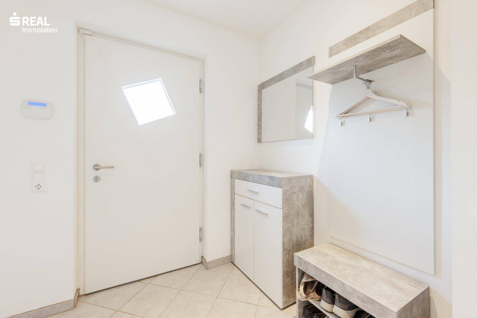 Eingangsbereich mit Garderobe, Spiegel und Fliesenboden.
