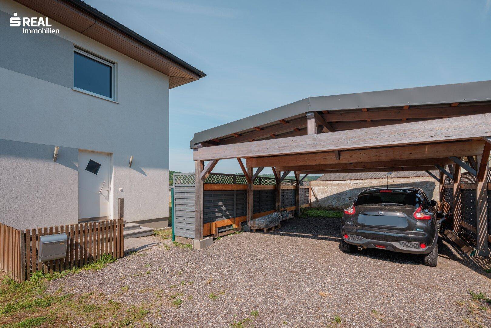 Carport mit Stellplatz für ein Fahrzeug und Zufahrt zum Haus.