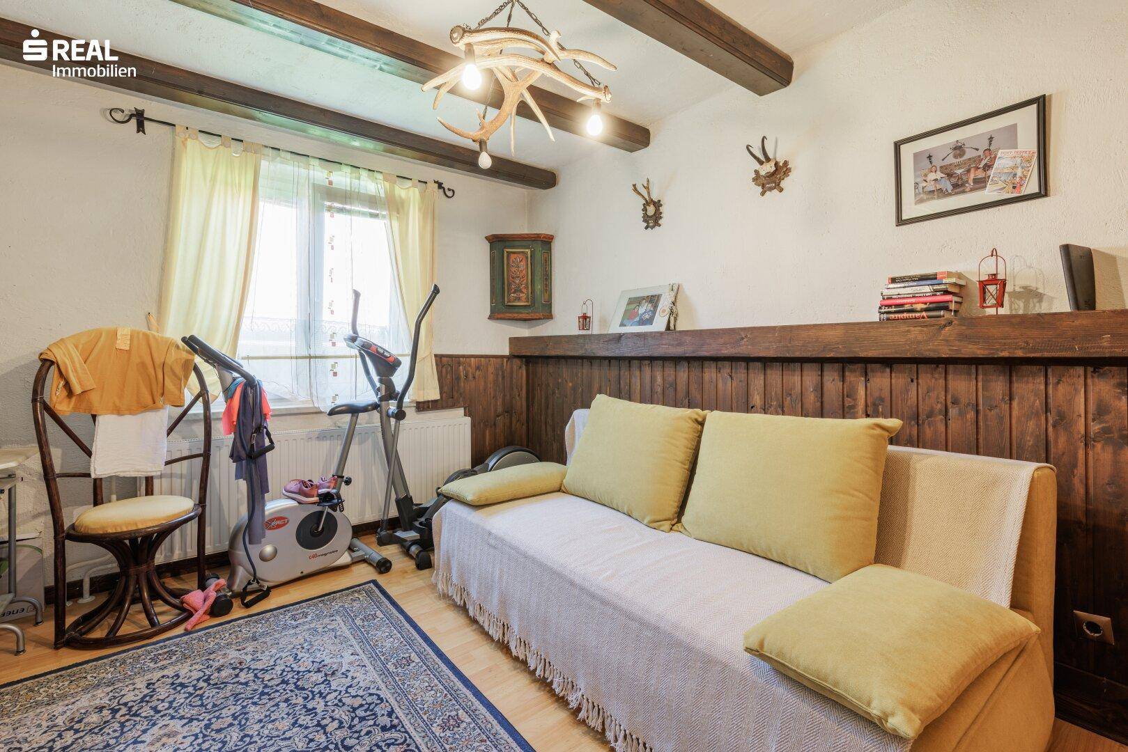 Raum mit Holzwänden, Sofa, Trainingsgeräten und traditioneller Hirschgeweih-Dekoration.