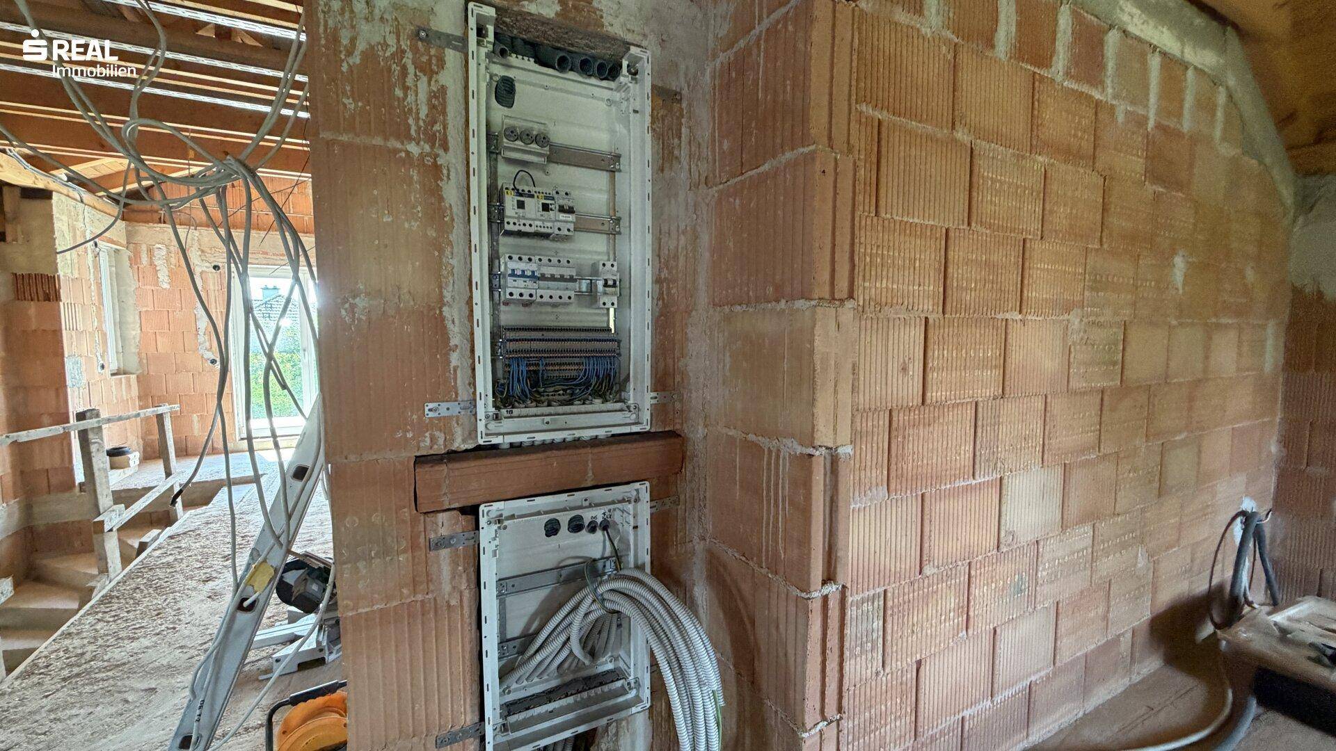 Elektrische Verteilung und Verkabelung in einem Technikraum im Rohbau.