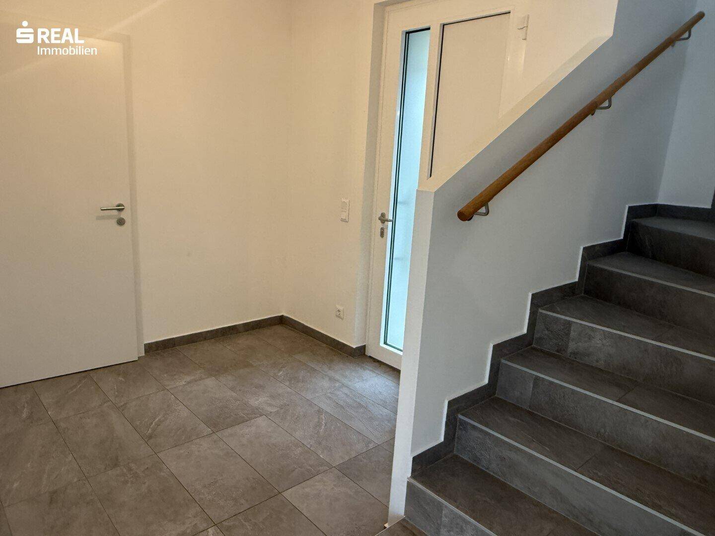 Heller Eingangsbereich mit Fliesenboden und Treppe zum Obergeschoss.