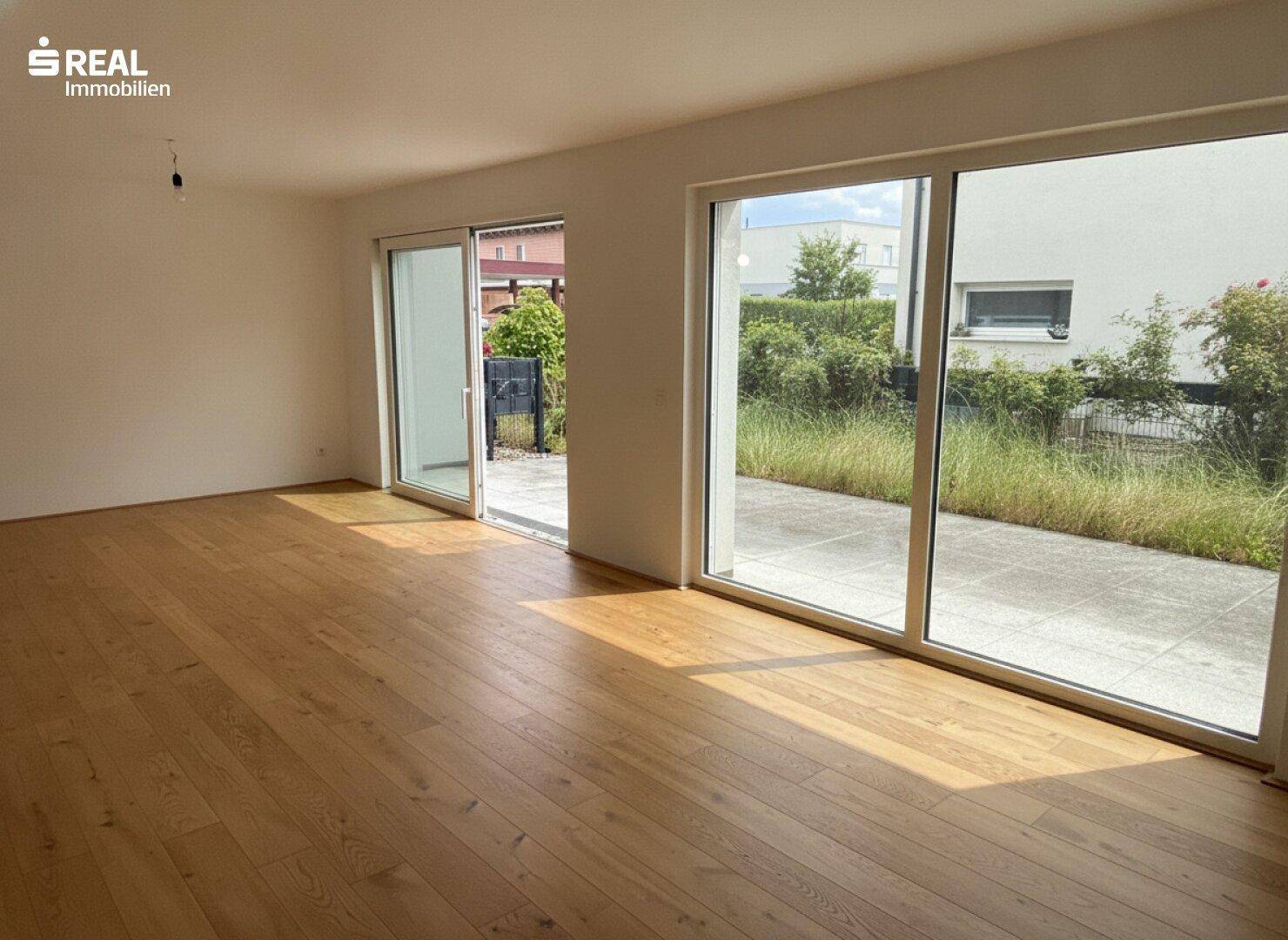 Helles Wohnzimmer mit Eichenparkett und großen Schiebetüren zur Terrasse.
