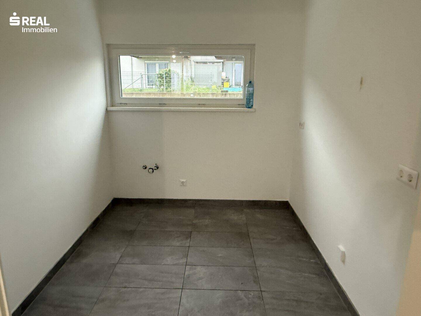 Kleiner Raum mit Fliesenboden und Fenster, ideal als Hauswirtschaftsraum nutzbar.