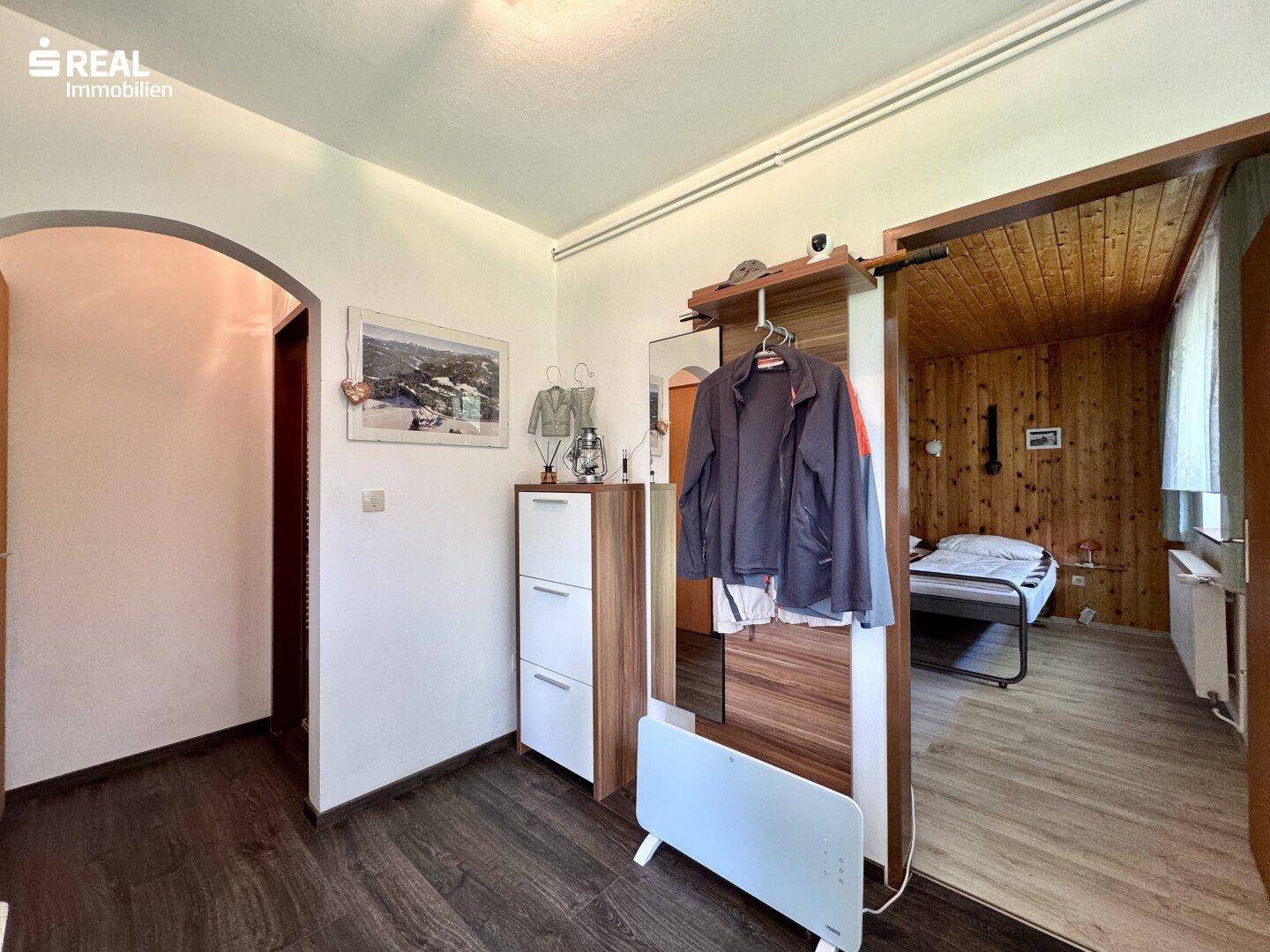 Heller Flur mit Holzfußboden und Garderobe, der zu einem Schlafzimmer führt.