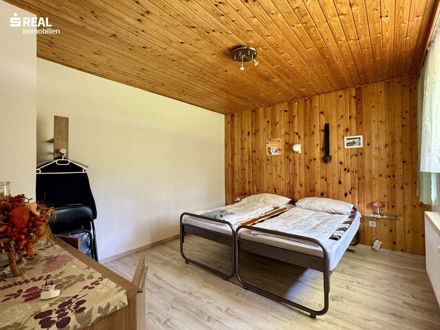 Schlafzimmer mit Holzwänden und Holzdecke, ausgestattet mit zwei Einzelbetten.