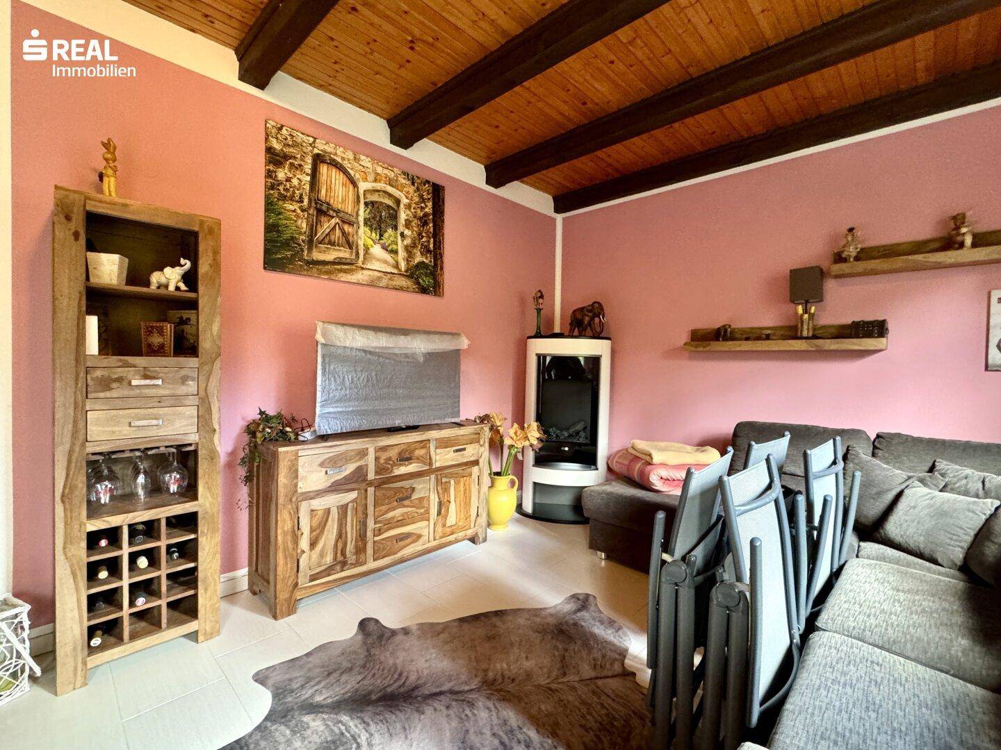 Gemütliches Wohnzimmer mit Holzbalkendecke, Kaminofen und rustikalen Holzmöbeln.