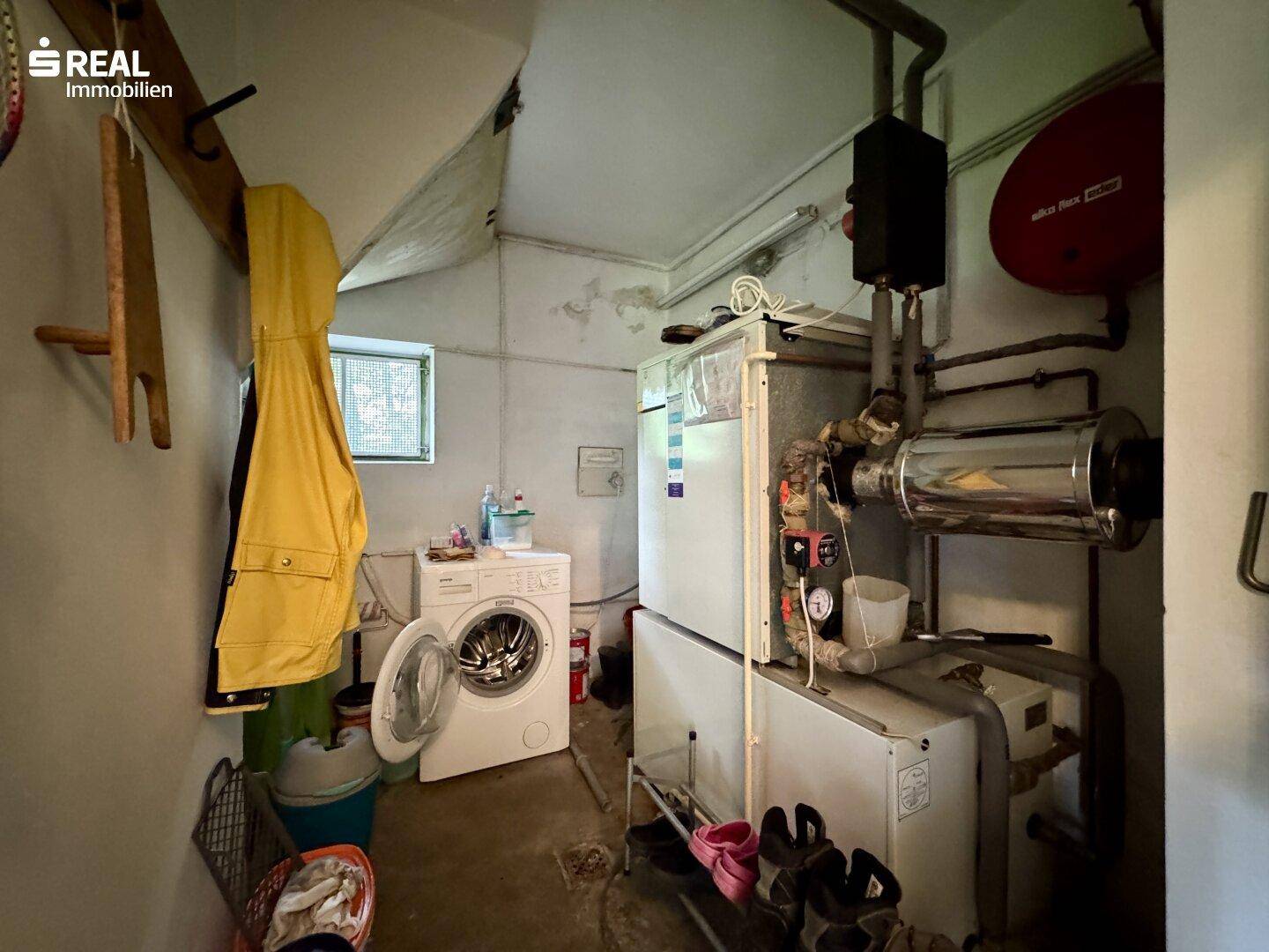 Hauswirtschaftsraum mit Waschmaschine, Trockner und Heizungsanlage im Kellerbereich.