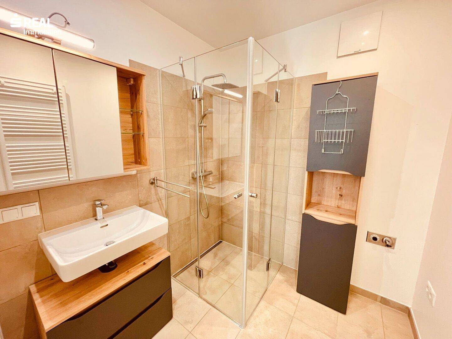 Modernes Badezimmer mit begehbarer Dusche, Einzelwaschbecken und beheiztem Handtuchhalter.