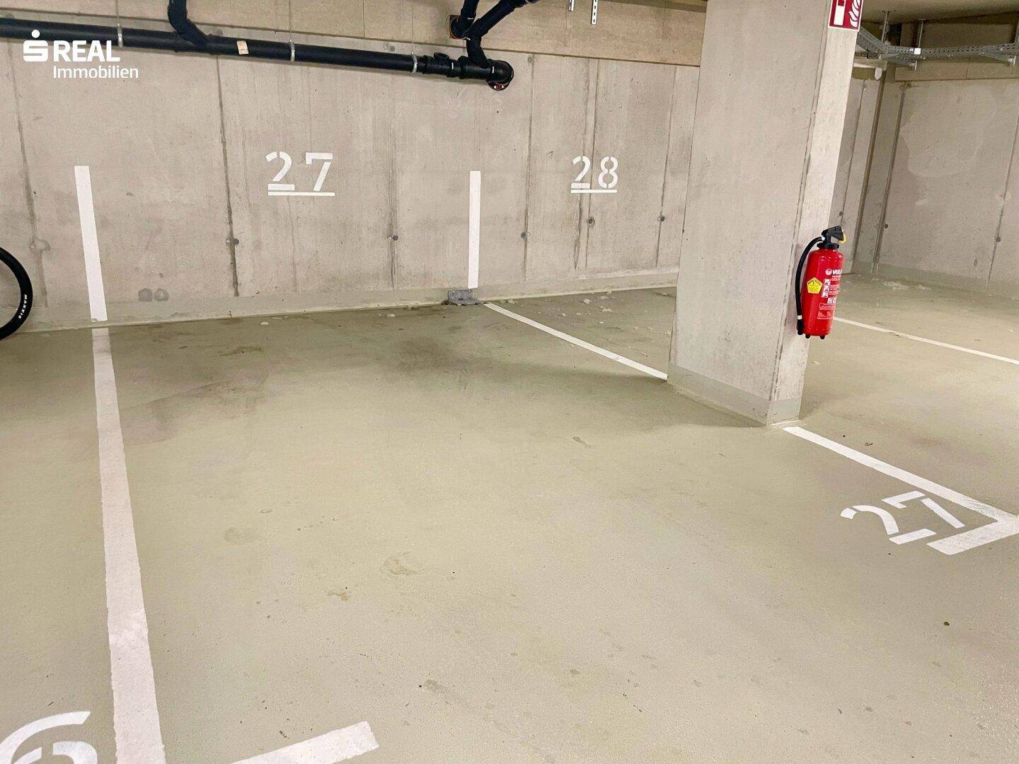 Tiefgaragenstellplatz mit klar markierten Parkflächen und Brandschutzvorrichtungen.