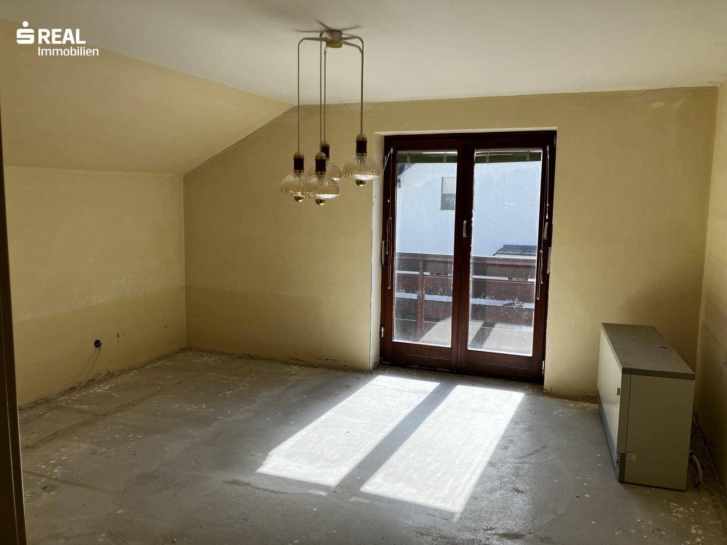 Heller Raum mit Balkonzugang und unfertigem Boden, ideal für ein Schlafzimmer.