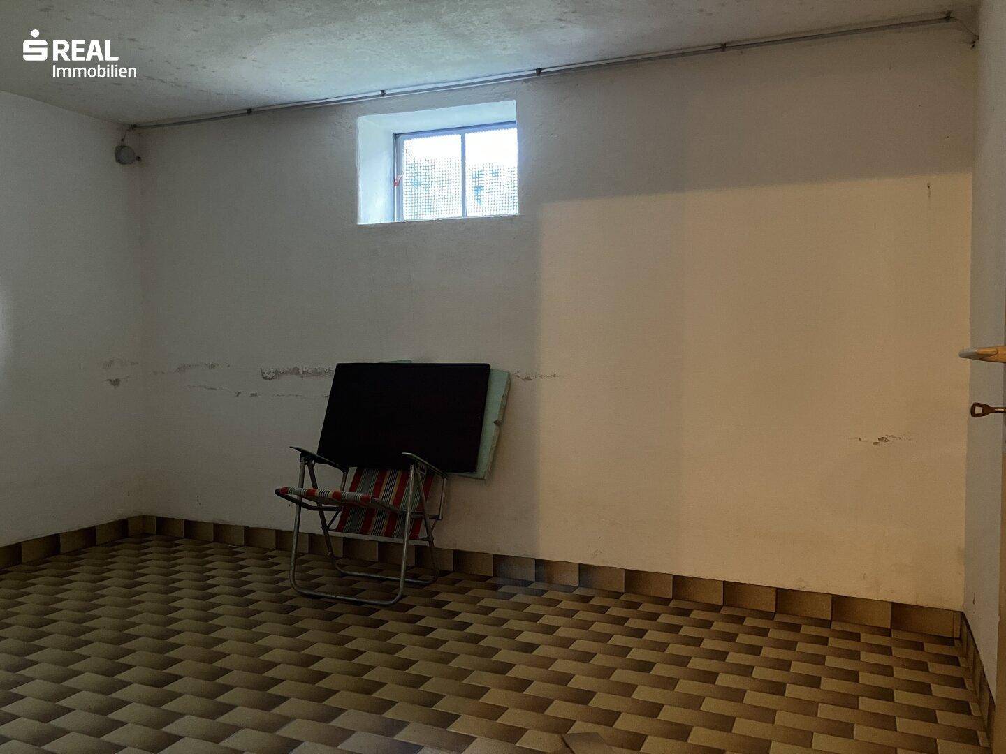 Kellerraum mit Fliesenboden und kleinem Fenster, bietet zusätzlichen Stauraum.