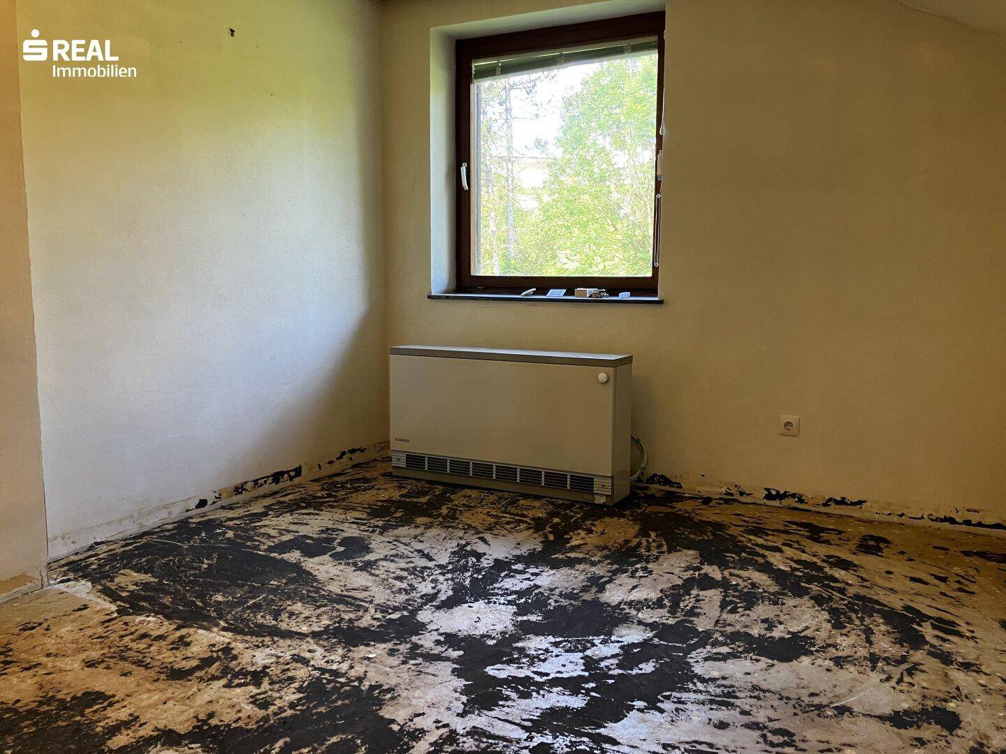 Schlafzimmer mit Fenster und unfertigem Boden, bereit für eine individuelle Gestaltung.