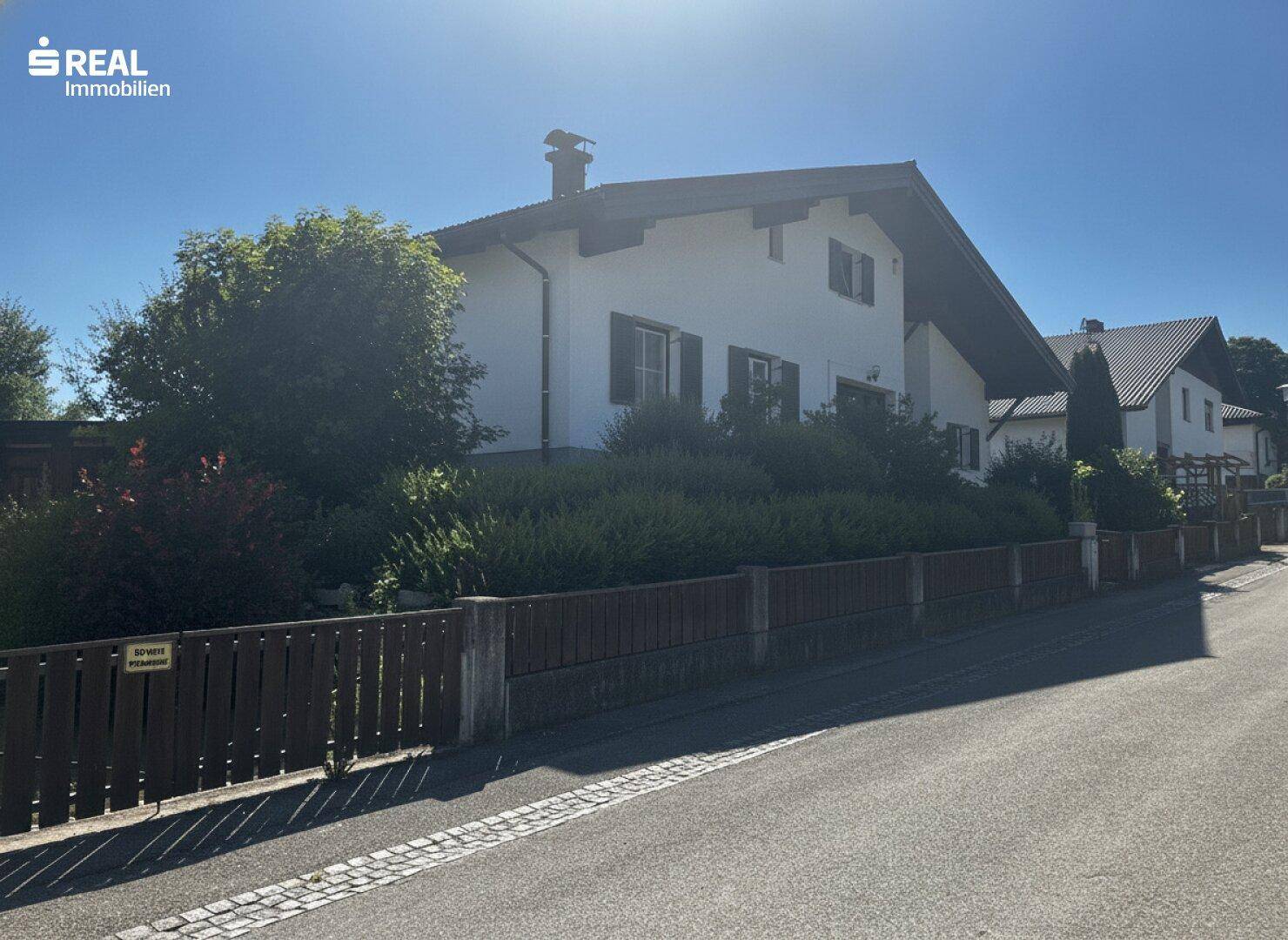 Ansicht des Einfamilienhauses von der Straße mit gepflegter Bepflanzung und Satteldach.