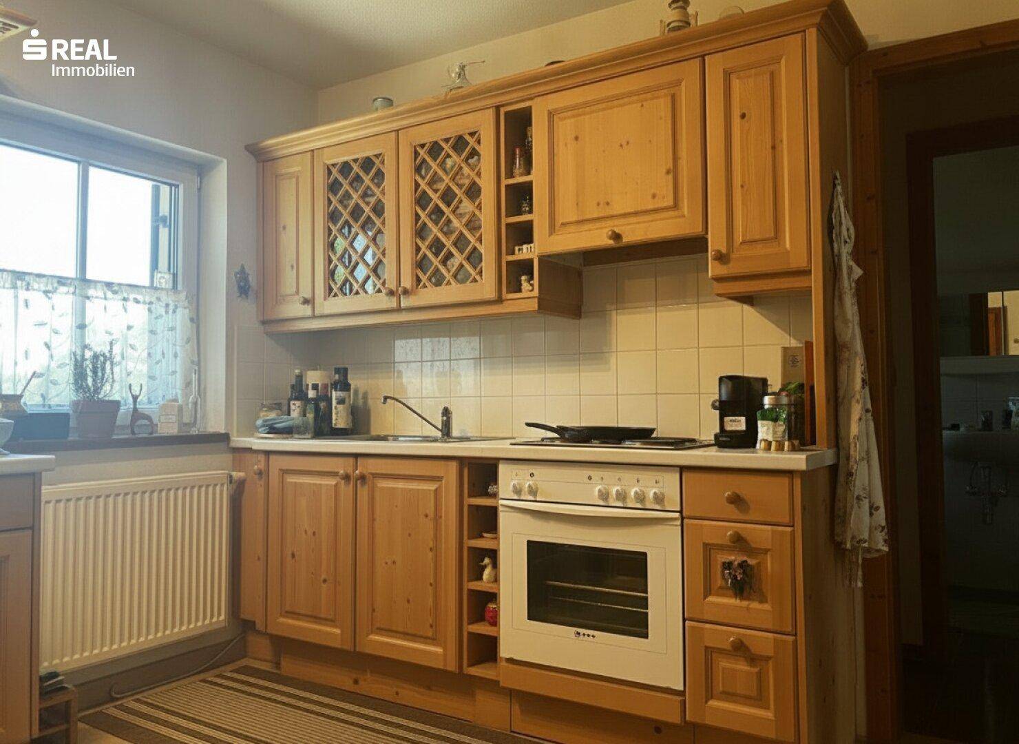 Traditionelle Holzküche mit Einbauschränken, weiß gefliestem Spritzschutz und Fenster.