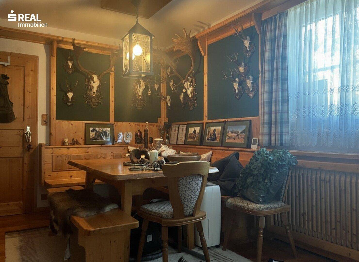 Gemütlicher Essbereich im alpinen Stil mit Holztäfelung, Eckbank und Hirschgeweihen.