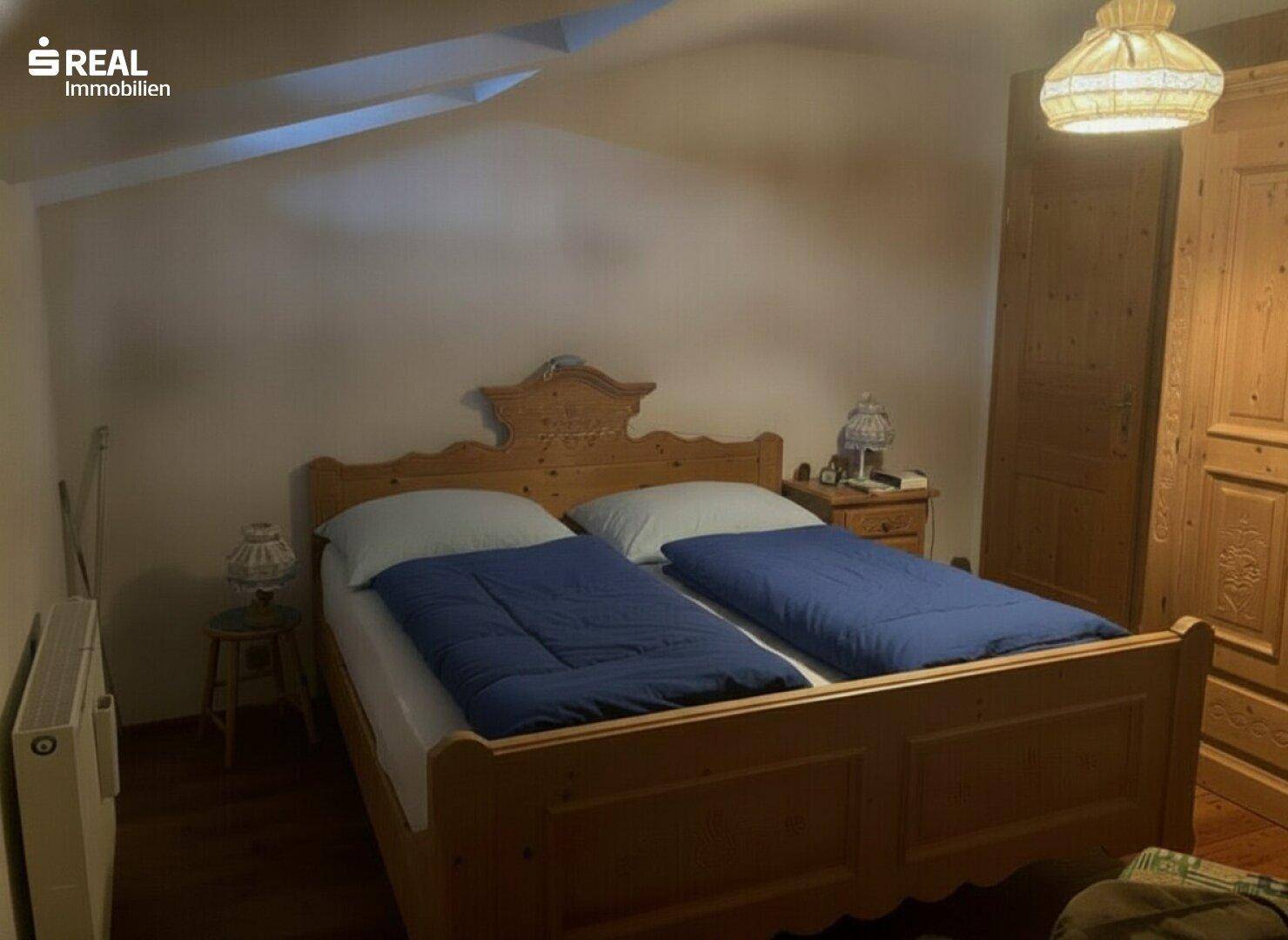Schlafzimmer mit traditionellem Holzdoppelbett, Nachttischen und Kleiderschrank.