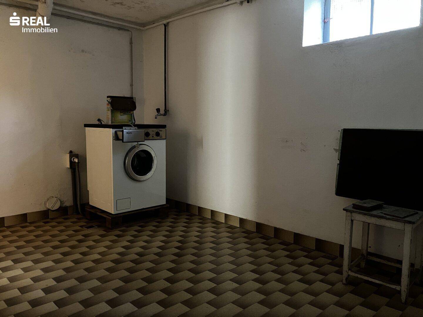 Waschküche im Keller mit Fliesenboden und Waschmaschine, praktisch für den Haushalt.