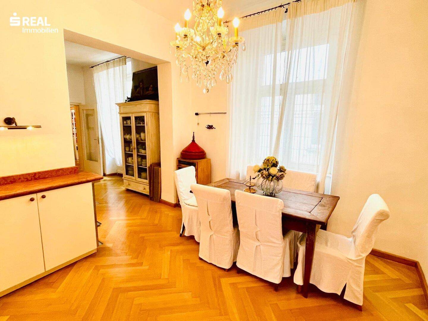 Eleganter Essbereich mit Kronleuchter, Fischgrätparkett und klassischem Mobiliar, ideal für gesellige Runden.
