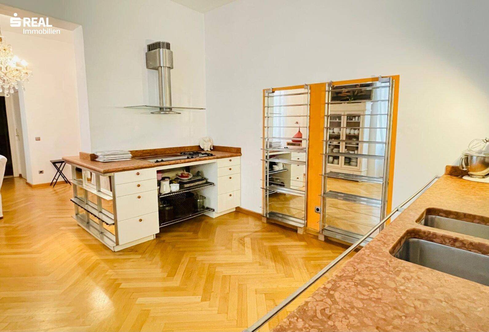 Offene Küche mit Kochinsel, Dunstabzugshaube und Fischgrätparkettboden, perfekt für moderne Wohnkonzepte.