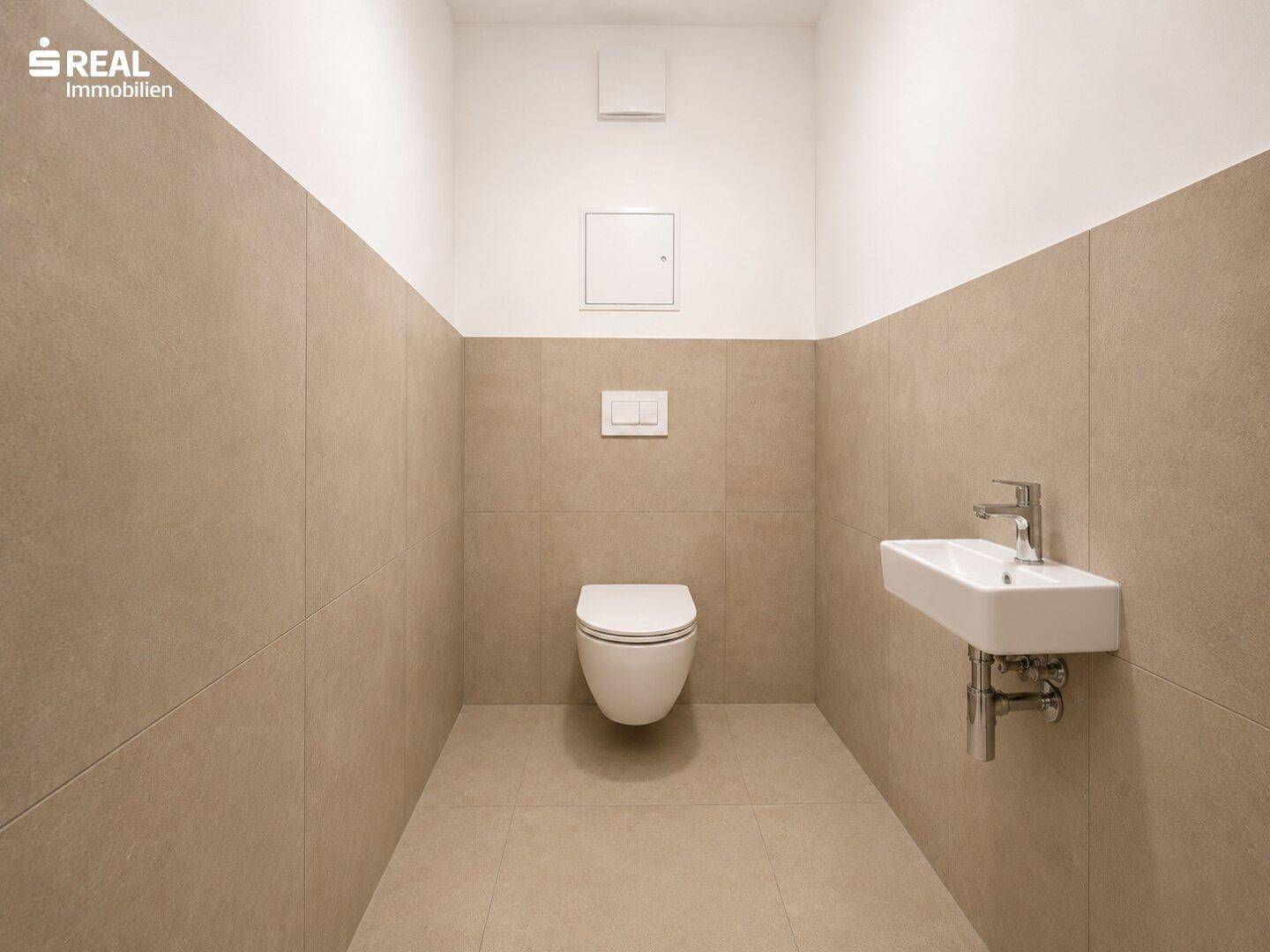 Funktionale Gästetoilette mit beigefarbenen Wandfliesen und einem wandhängenden WC.