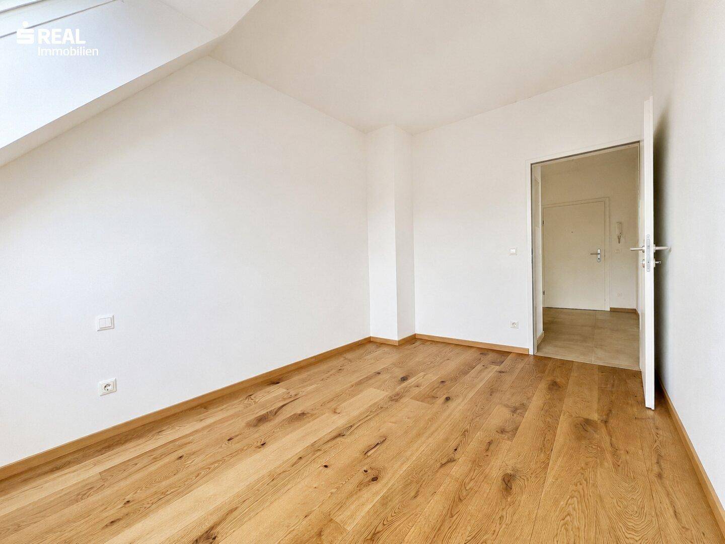 Helles Zimmer mit Holzboden und weiß gestrichenen Wänden, ideal als Schlaf- oder Kinderzimmer.