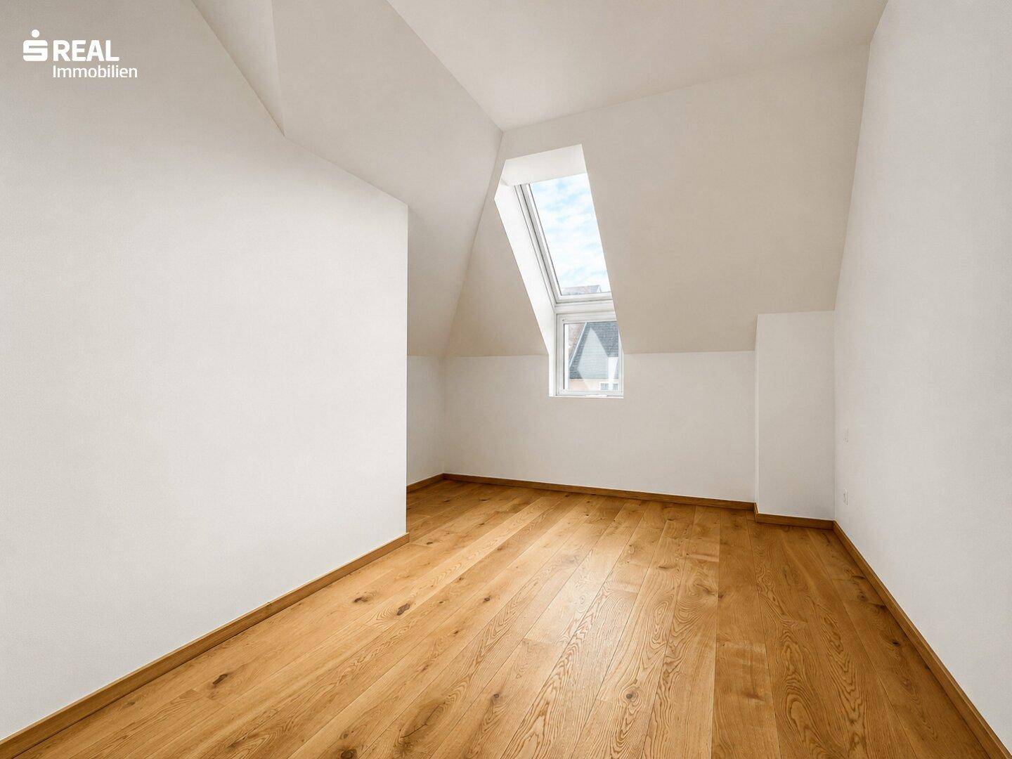 Ruhiges Zimmer im Dachgeschoss mit Holzboden und Dachfenster, bietet viel Tageslicht.