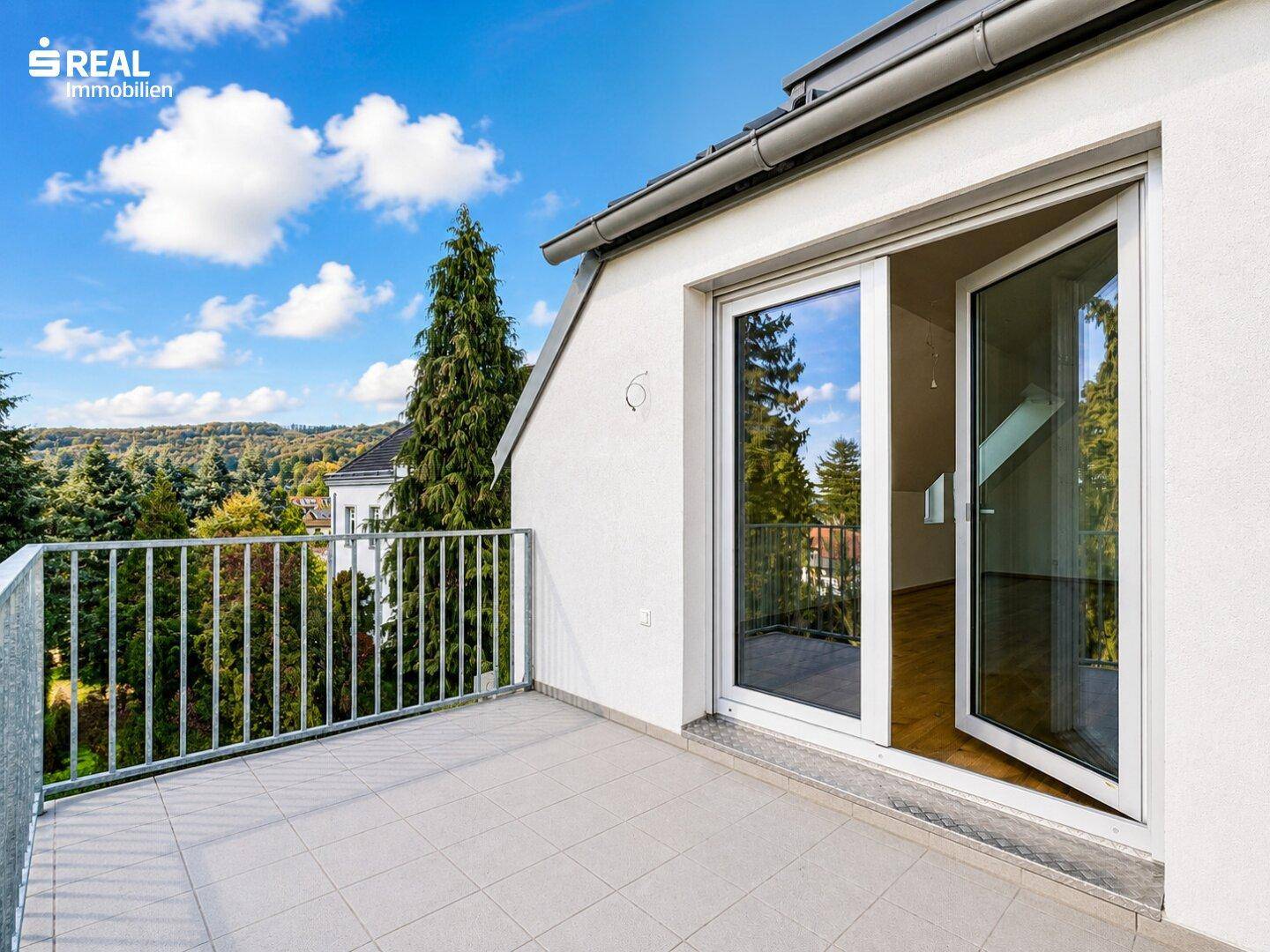Geräumiger Balkon mit Fliesenboden und weitem Blick ins Grüne und auf die umliegende Landschaft.