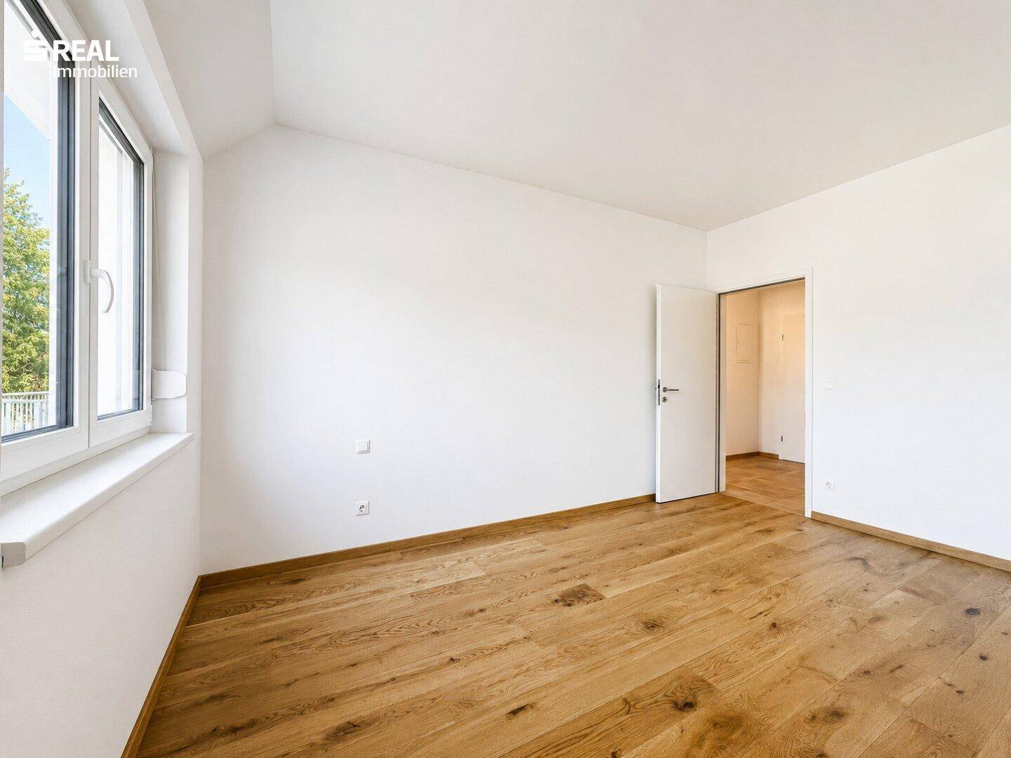 Freundliches Zimmer mit hellem Holzboden und weiß gestrichenen Wänden, bereit zur individuellen Gestaltung.
