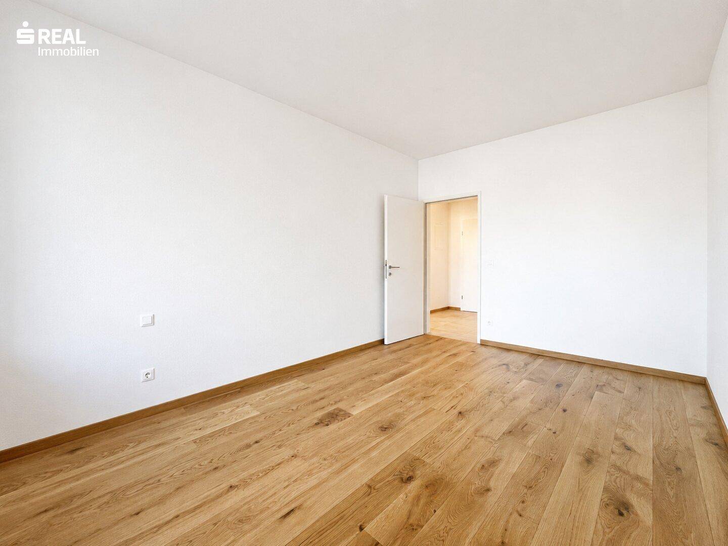 Geräumiges Zimmer mit hellem Holzboden und weißen Wänden, ideal als Schlaf- oder Kinderzimmer.