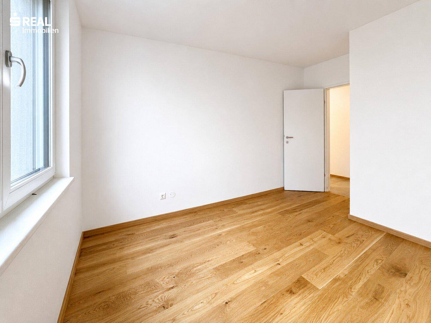 Geräumiges Zimmer mit Holzboden und weiß gestrichenen Wänden, bereit zur individuellen Gestaltung.