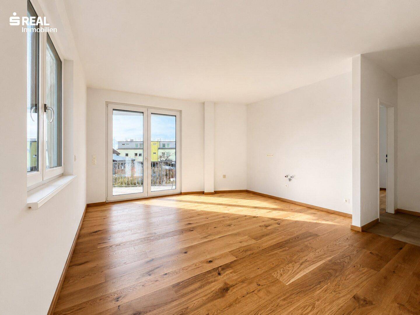 Heller Wohnbereich mit neuem Eichenparkettboden und großzügigem Zugang zum Balkon.