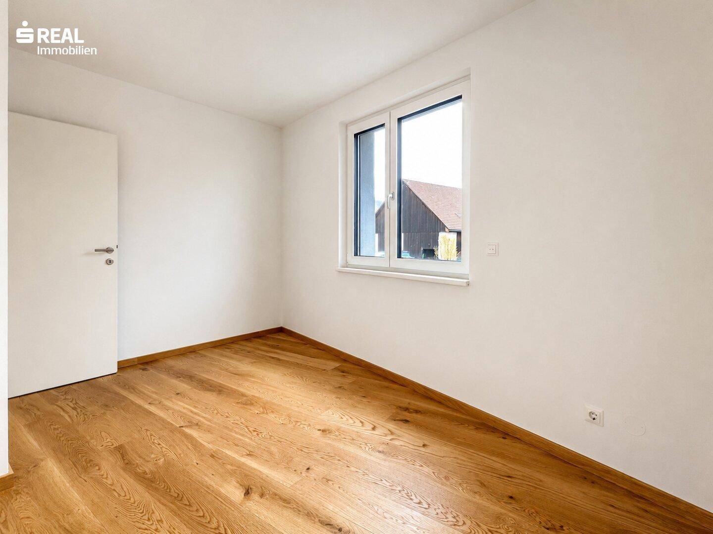 Schlichtes Zimmer mit Holzboden und weiß gestrichenen Wänden, bietet viel Gestaltungspotenzial.